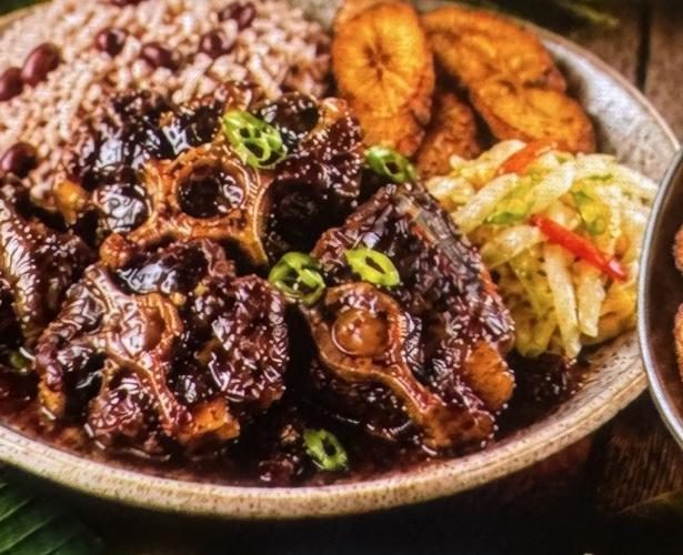 Jamaican oxtail in rich brown gravy with rice and peas, fried plantains and steamed cabbage